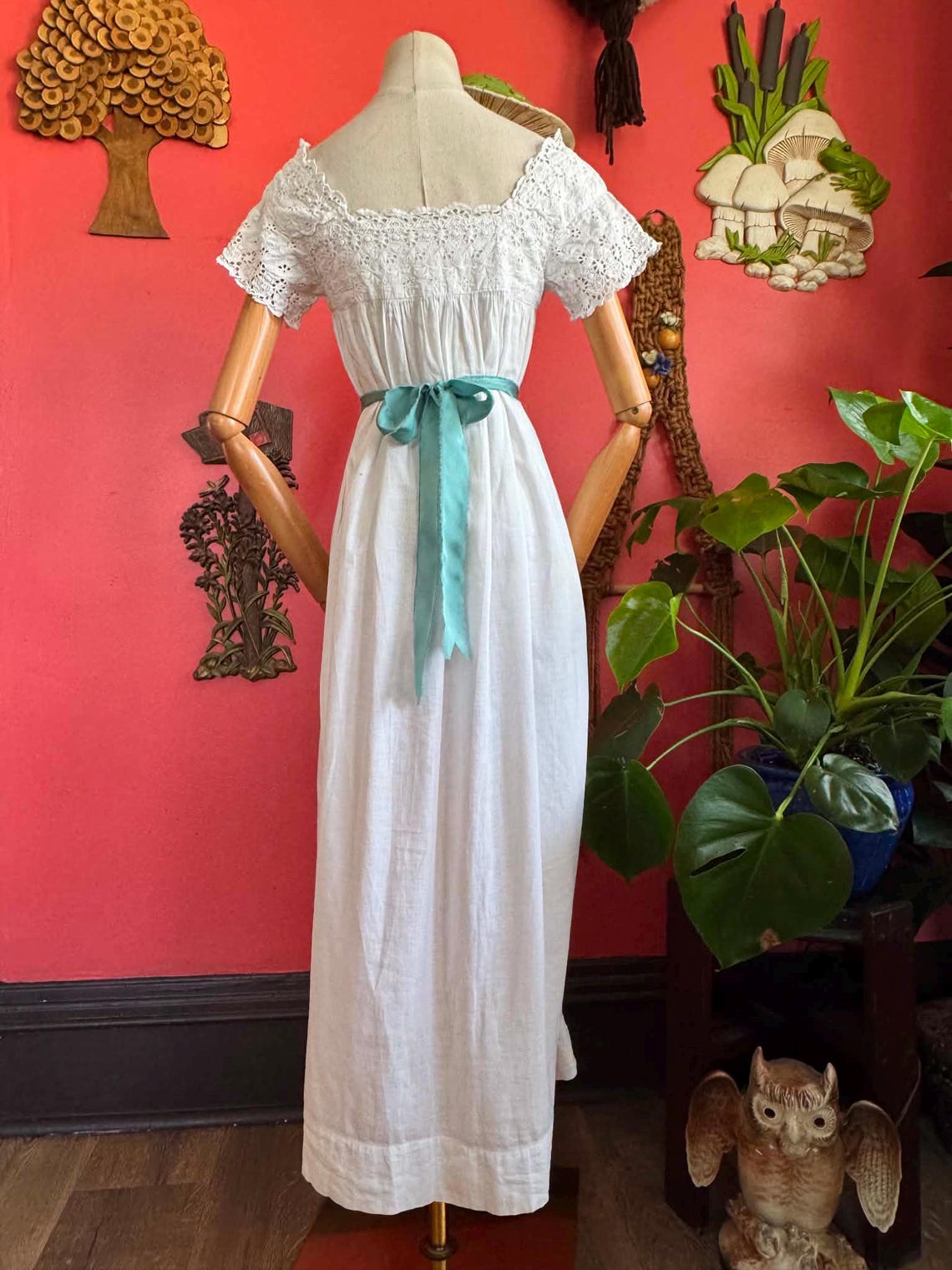 1900s white gown with lace details and blue ribbons.